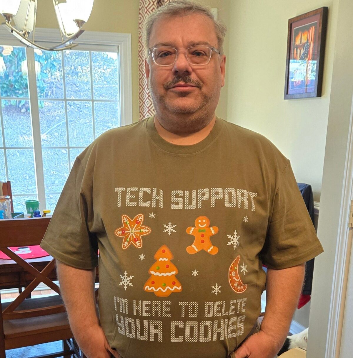 A picture of the author wearing a T-shirt that looks like an ugly Christmas Sweater. It has several Christmas cookies on it